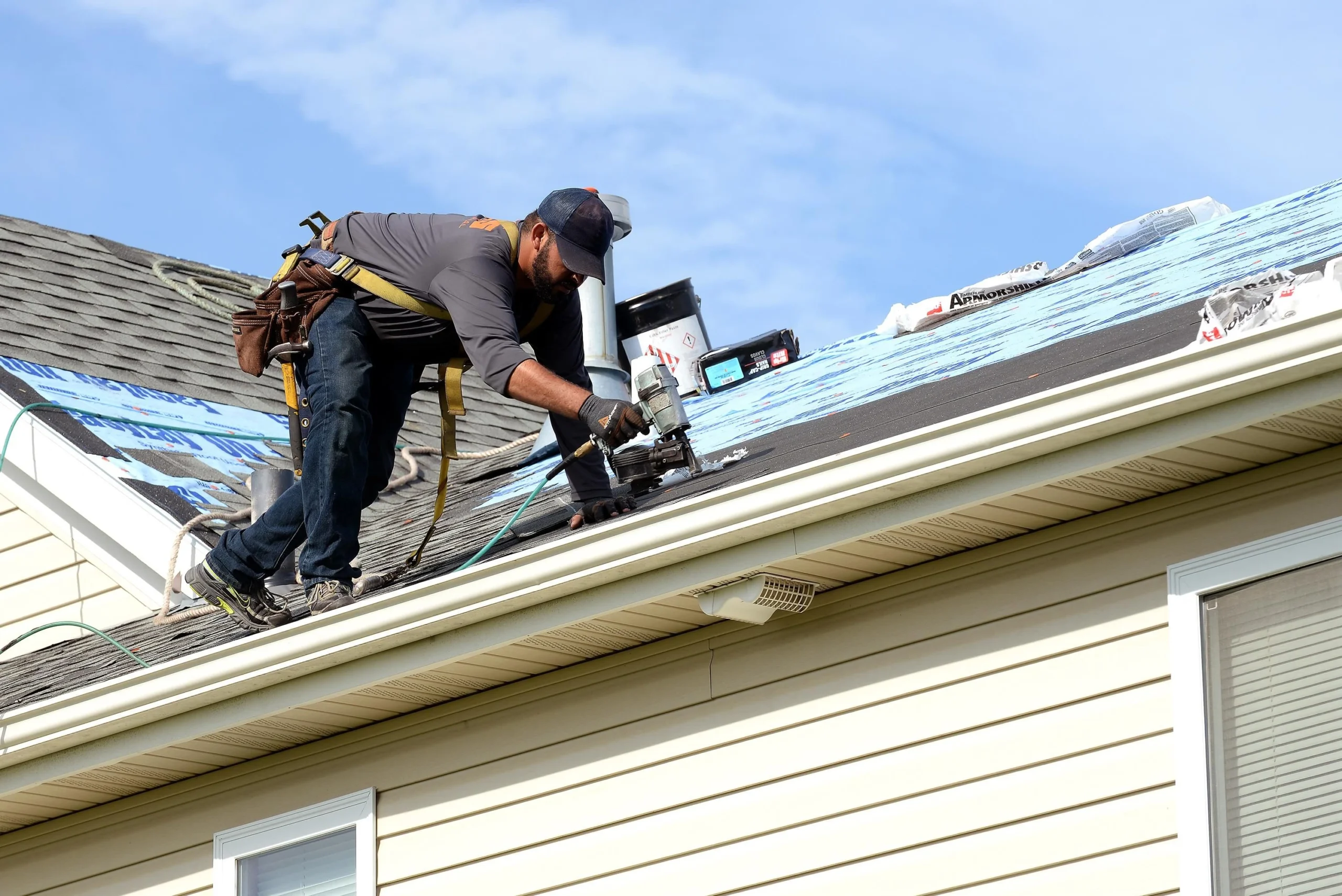 emergency roof repair services Roof repair technician fixing a residential roof leak using a nail gun during shingle replacement on a Texas home